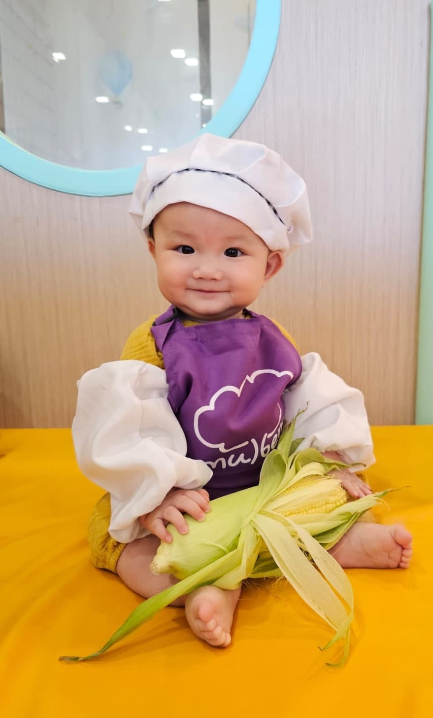 A Mulberry Learning child in a purple chef's apron, smiling